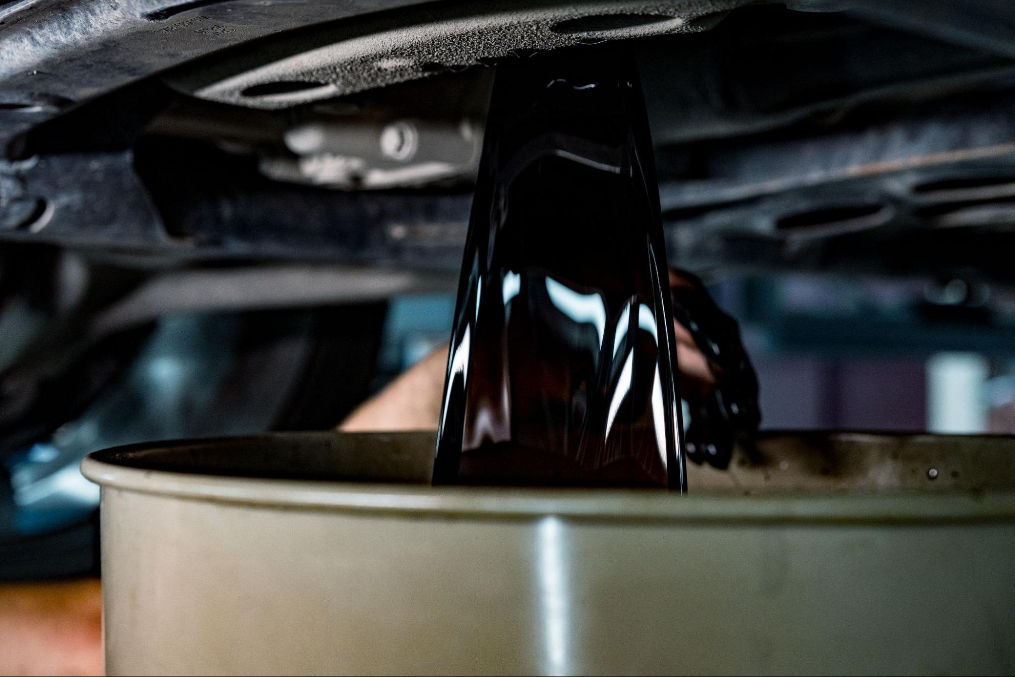 Dirty engine oil draining during a car oil change, close-up view